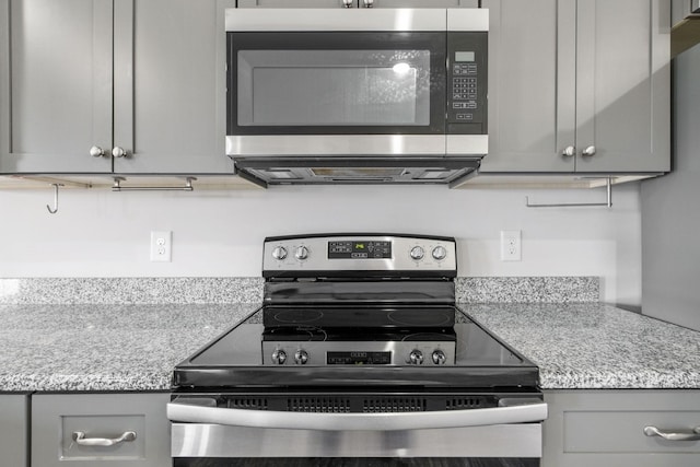 kitchen with gray cabinets, appliances with stainless steel finishes, and light stone countertops