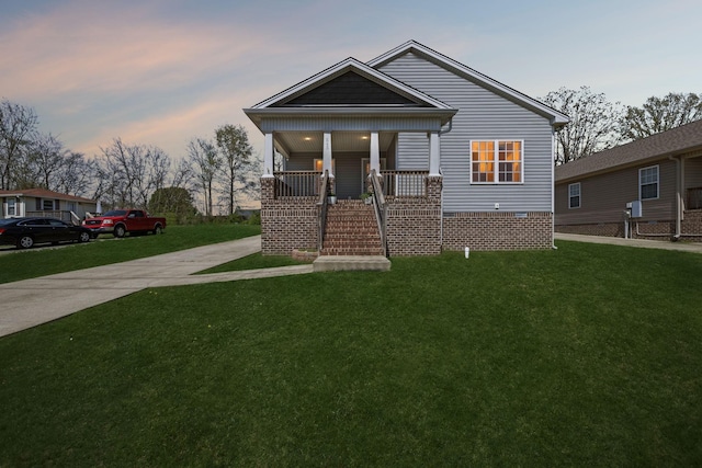 bungalow-style home with concrete driveway, a porch, crawl space, and a lawn