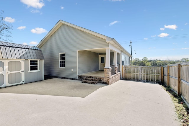 rear view of property featuring a shed, a patio area, fence, and an outbuilding