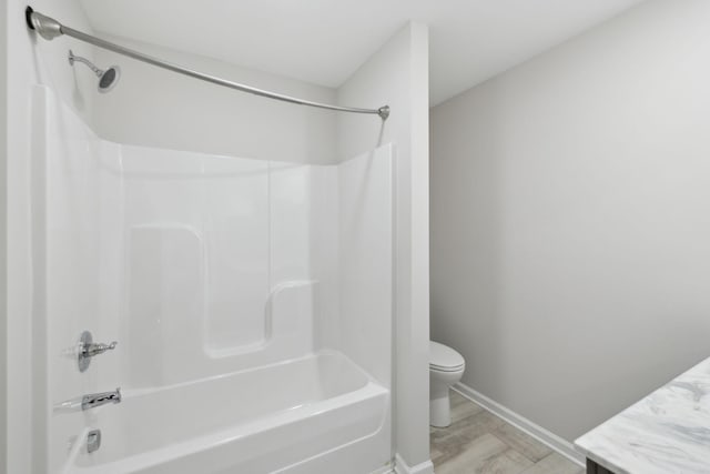 bathroom featuring shower / washtub combination, vanity, toilet, wood finished floors, and baseboards