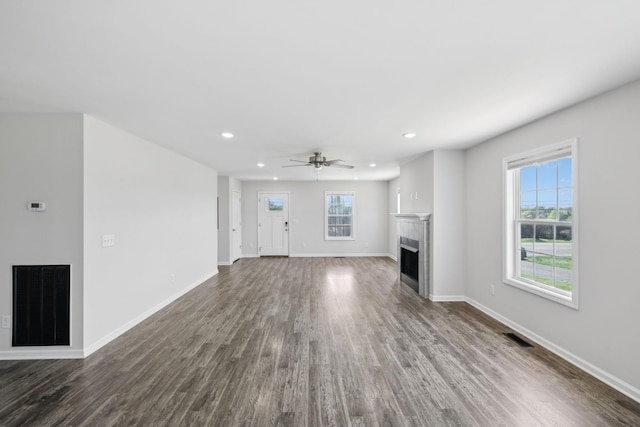 unfurnished living room featuring visible vents, baseboards, dark wood-style flooring, a fireplace, and recessed lighting