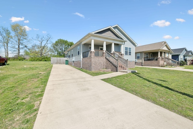 view of front of home with a front yard, a porch, fence, and driveway