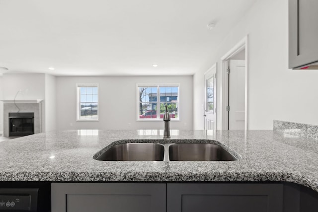 kitchen with a sink, open floor plan, recessed lighting, gray cabinetry, and light stone counters
