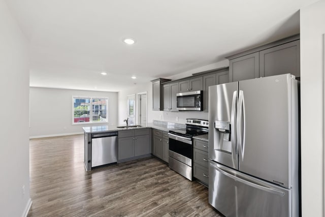 kitchen with a sink, appliances with stainless steel finishes, dark wood-style floors, recessed lighting, and gray cabinetry