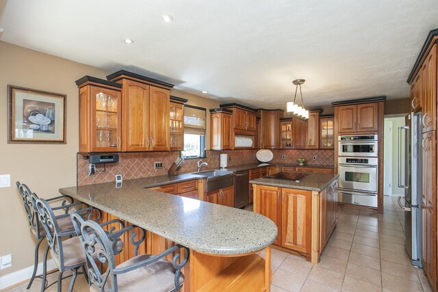 1035 Forest Harbor Dr, Hendersonville, TN 37075 - kitchen with brown cabinetry, tasteful backsplash, a kitchen bar, a peninsula, and appliances with stainless steel finishes