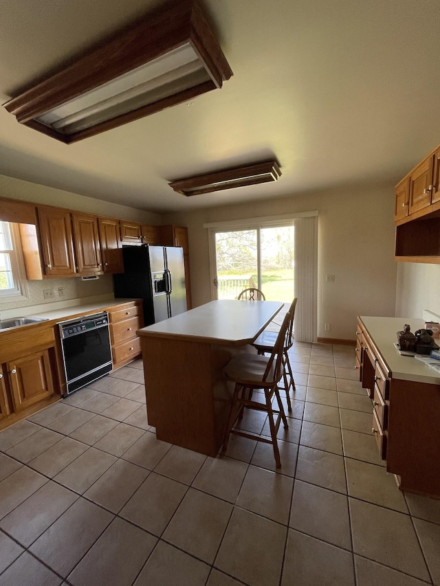 kitchen featuring light tile patterned floors, black dishwasher, light countertops, refrigerator with ice dispenser, and a kitchen island
