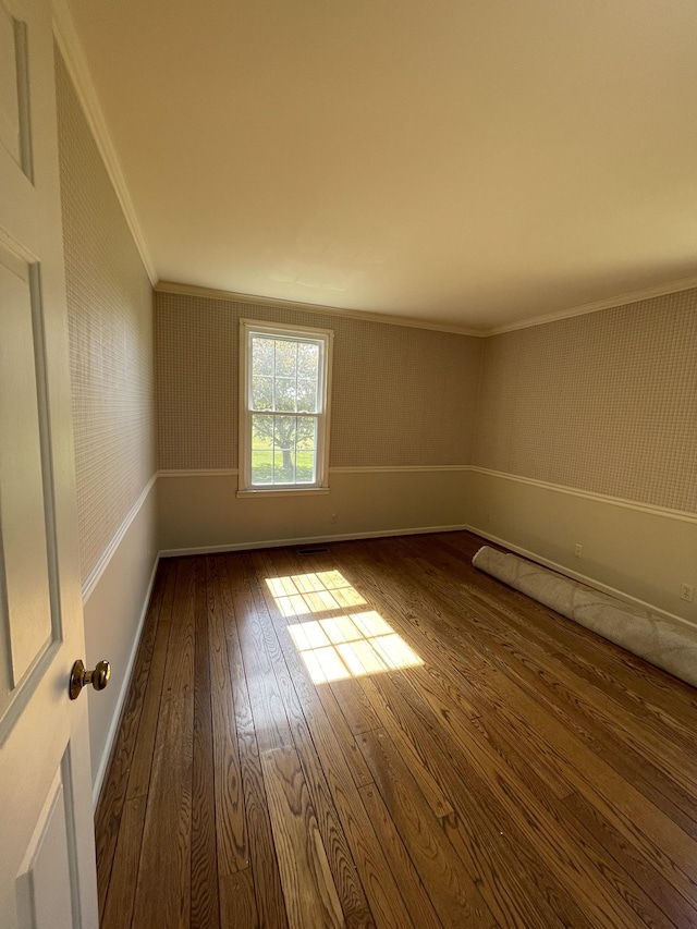 empty room with dark wood-type flooring, baseboards, and ornamental molding