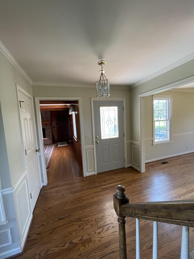 entryway with a wealth of natural light, ornamental molding, and wood finished floors