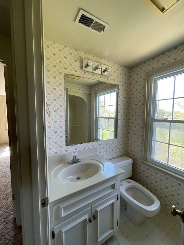 bathroom featuring visible vents, toilet, vanity, wallpapered walls, and tile patterned floors