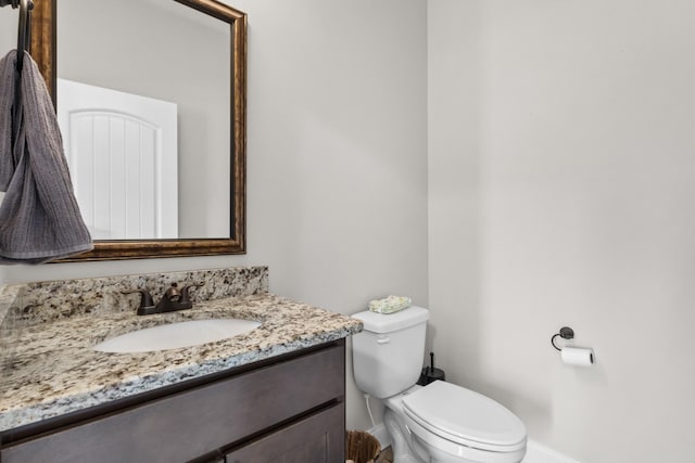 bathroom with baseboards, vanity, and toilet