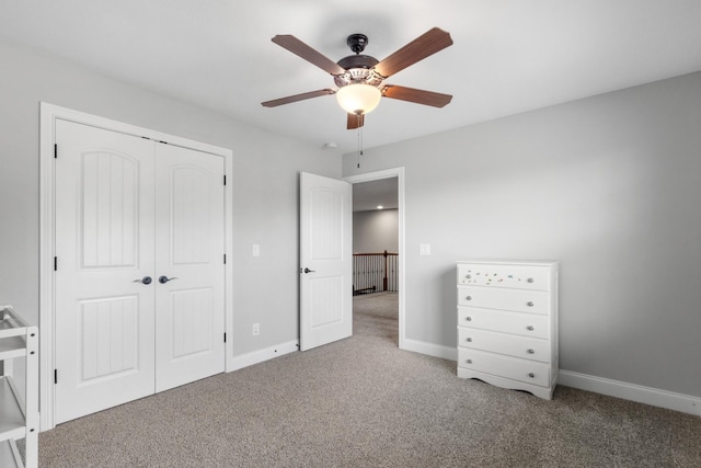 unfurnished bedroom with a closet, carpet flooring, baseboards, and a ceiling fan