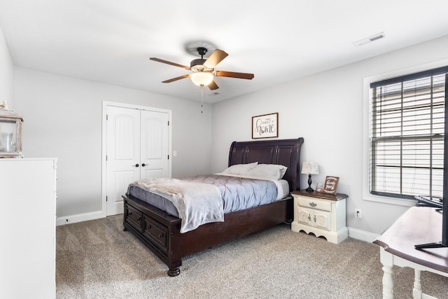 carpeted bedroom with a closet, visible vents, baseboards, and ceiling fan