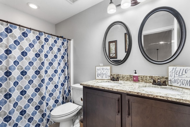 bathroom with toilet, visible vents, a sink, and double vanity