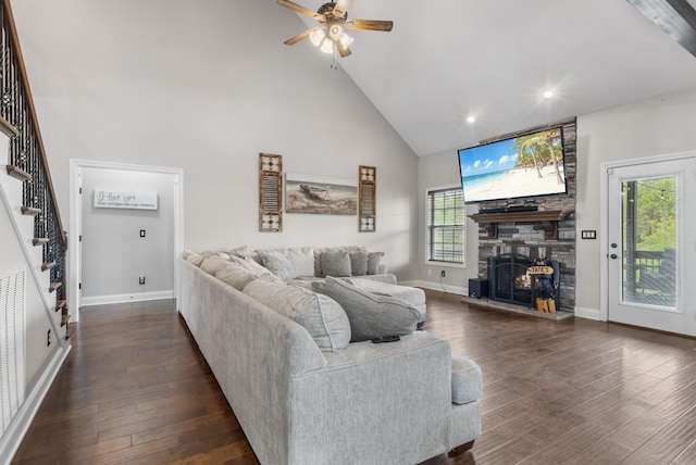living room with dark wood-style flooring, high vaulted ceiling, a ceiling fan, stairway, and a fireplace