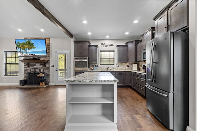 kitchen with stainless steel appliances, open shelves, a kitchen island, light stone countertops, and dark brown cabinetry