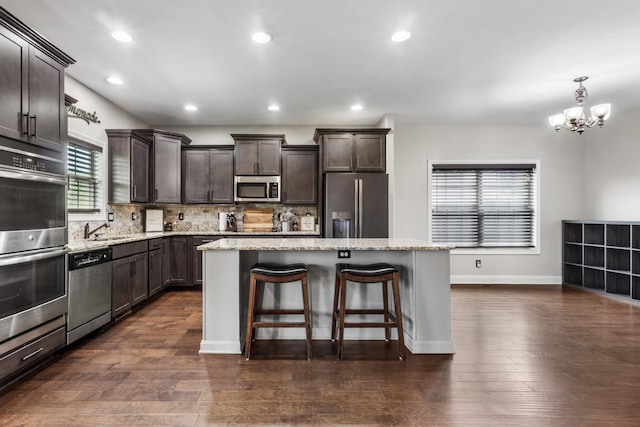 kitchen with an inviting chandelier, a sink, a center island, dark brown cabinetry, and appliances with stainless steel finishes
