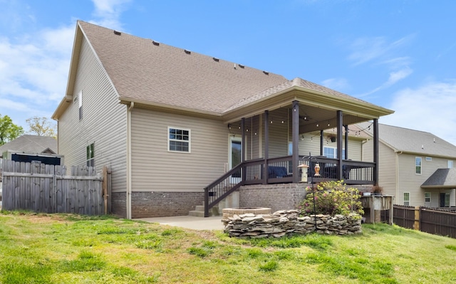 rear view of house featuring fence, a lawn, roof with shingles, and a patio