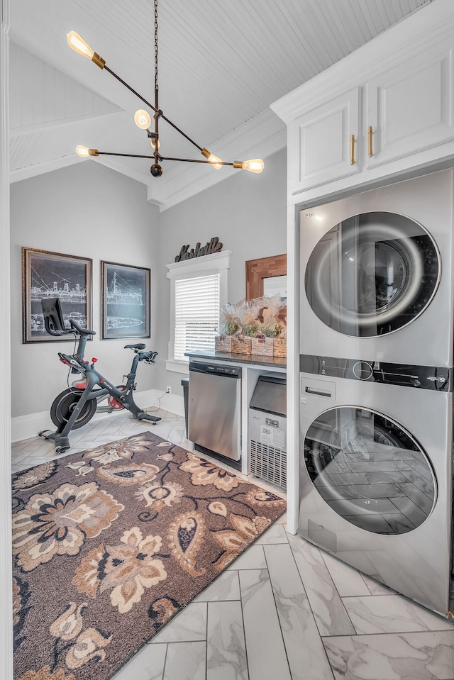 washroom featuring marble finish floor, stacked washer / dryer, laundry area, ornamental molding, and a notable chandelier