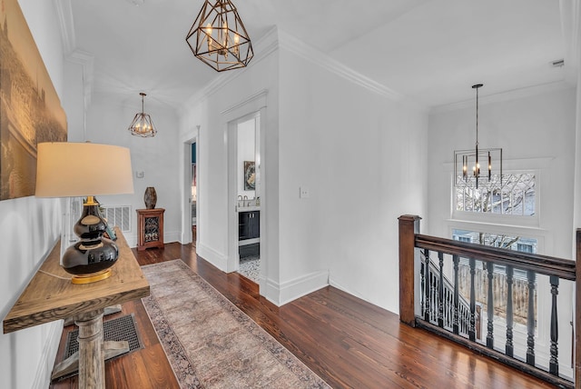 corridor featuring hardwood / wood-style flooring, an inviting chandelier, an upstairs landing, and visible vents