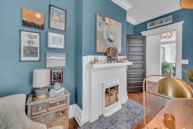 sitting room with a fireplace, wood finished floors, crown molding, and an inviting chandelier