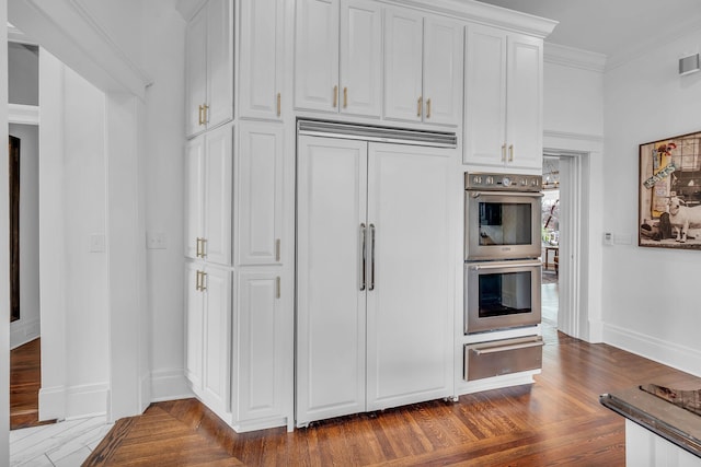 kitchen with double oven, white cabinets, a warming drawer, paneled built in fridge, and baseboards