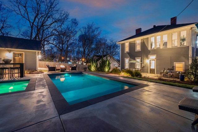 pool at dusk featuring fence, an outdoor hangout area, a fenced in pool, and a patio