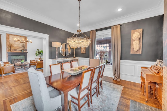 dining area featuring wainscoting, a notable chandelier, wood finished floors, and crown molding