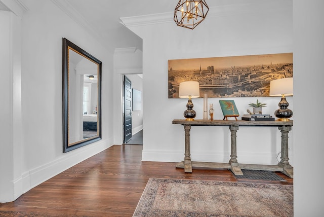 hallway with wood finished floors, crown molding, baseboards, and a notable chandelier
