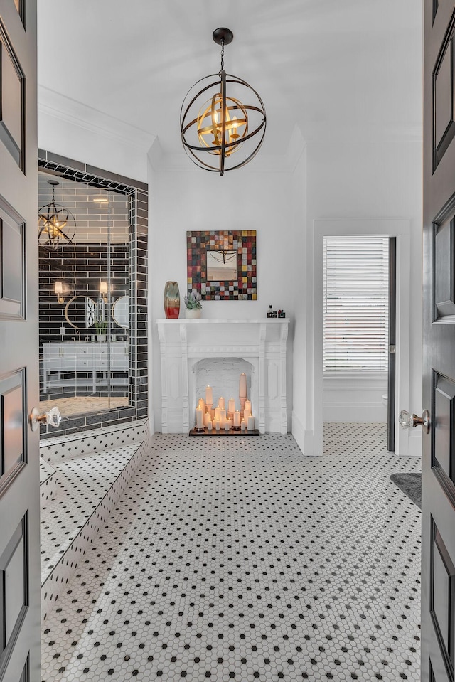living room featuring baseboards, a lit fireplace, ornamental molding, and an inviting chandelier