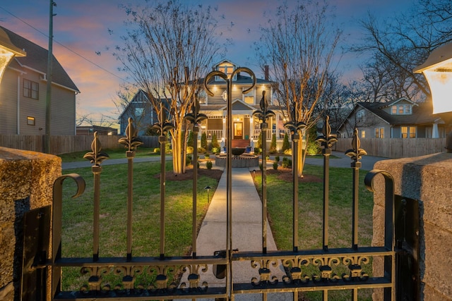 gate at dusk with fence and a yard