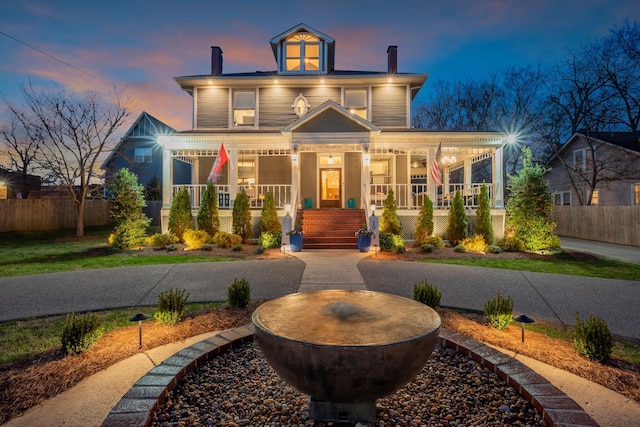 american foursquare style home with a porch, fence, and a chimney