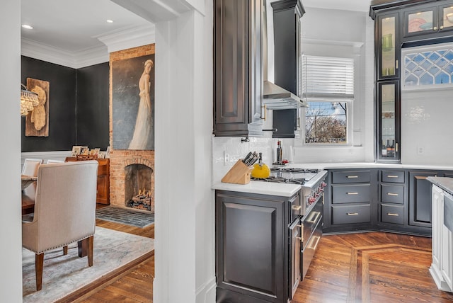 kitchen featuring ventilation hood, tasteful backsplash, glass insert cabinets, light countertops, and ornamental molding