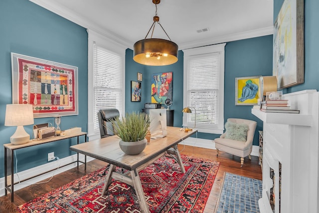 home office with baseboards, ornamental molding, wood finished floors, and visible vents