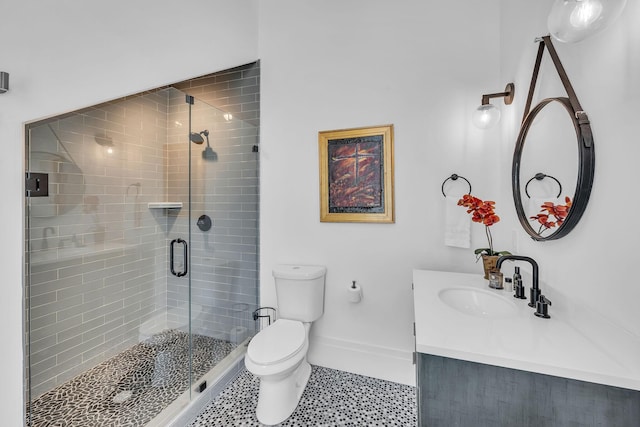 bathroom with baseboards, toilet, vanity, and a stall shower
