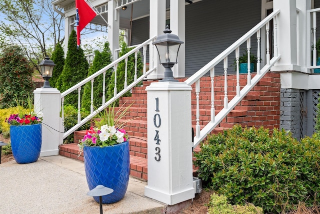 entrance to property featuring a porch and brick siding
