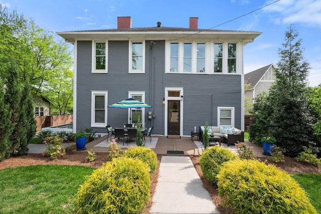 back of property featuring an outdoor living space, a chimney, and fence