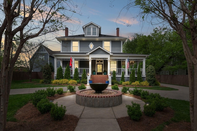 view of front facade featuring a porch, a chimney, and fence