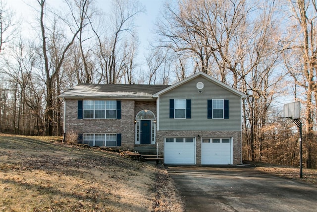 split foyer home featuring brick siding, driveway, and an attached garage