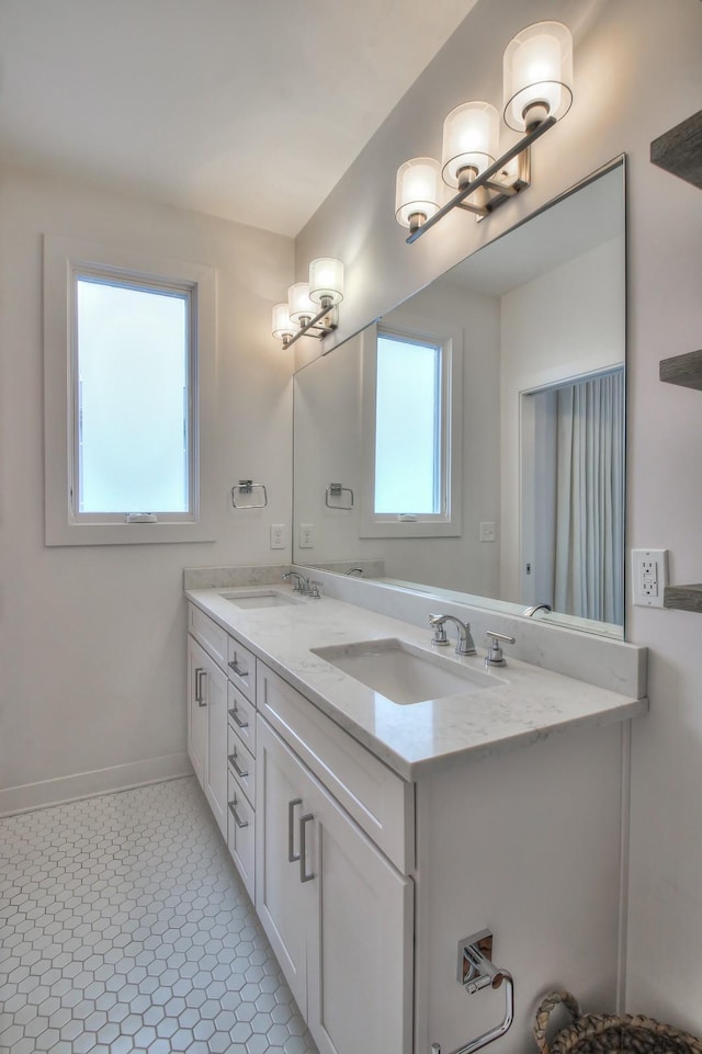 full bath with double vanity and baseboards