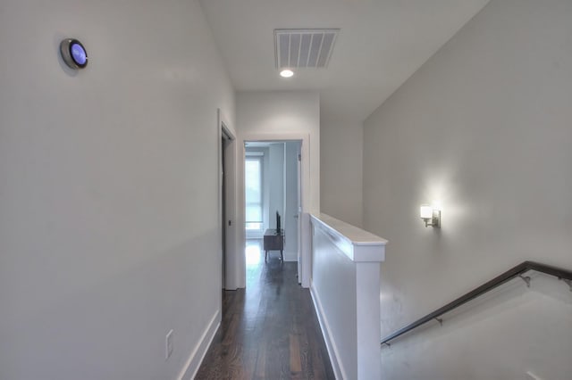 corridor featuring an upstairs landing, dark wood-type flooring, and baseboards