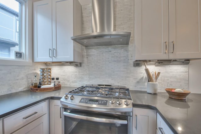 kitchen with stainless steel gas range, wall chimney range hood, tasteful backsplash, and dark countertops