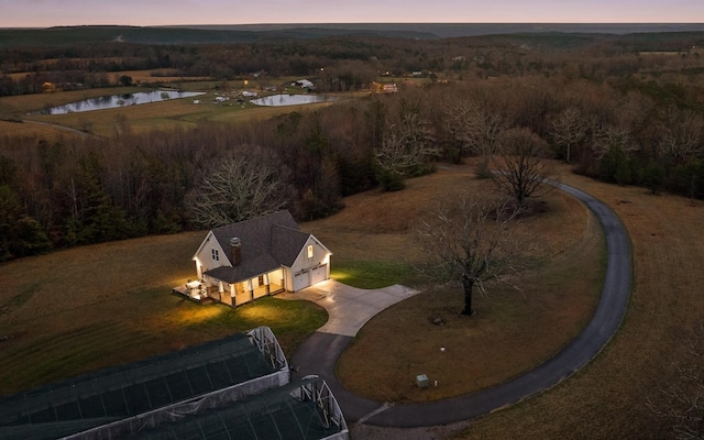 aerial view at dusk featuring a water view and a forest view