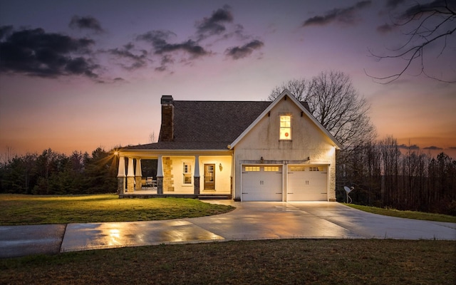view of front of property featuring concrete driveway, a chimney, a front lawn, a garage, and covered porch