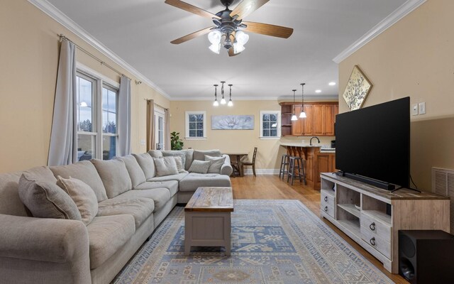 living room with ornamental molding, ceiling fan, wood finished floors, and baseboards