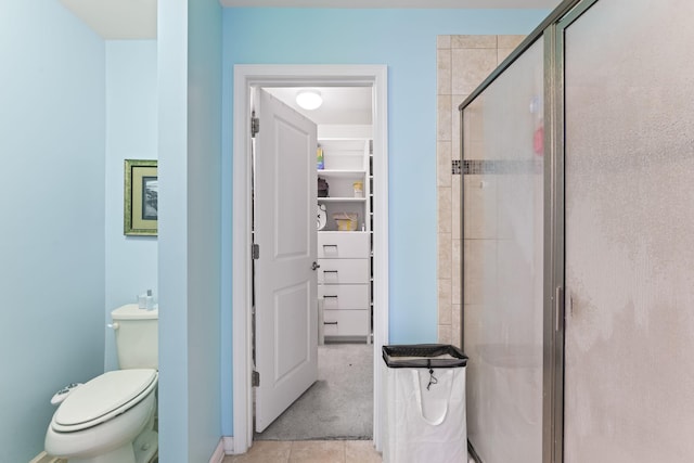 bathroom with toilet, tile patterned floors, and a shower stall