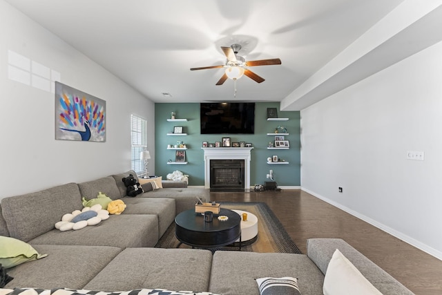 living area featuring baseboards, a fireplace, a ceiling fan, and wood finished floors