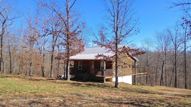 view of front of house featuring a forest view, a porch, and metal roof