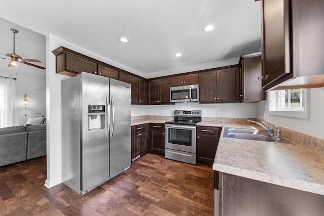 kitchen featuring appliances with stainless steel finishes, dark wood-style floors, dark brown cabinets, ceiling fan, and a sink