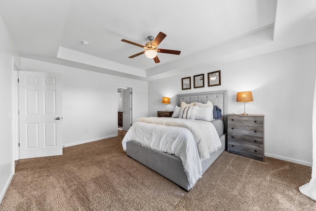 bedroom with a tray ceiling, baseboards, and carpet floors