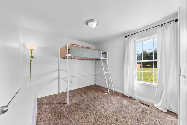 unfurnished bedroom featuring carpet flooring, baseboards, multiple windows, and visible vents